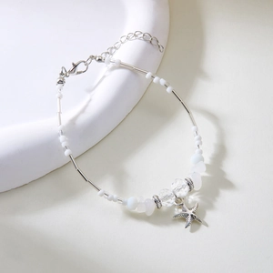 Detail van kralen en grind ketting met zeester hanger op een witte stenen standaard
