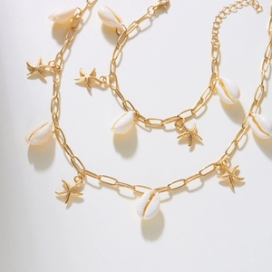 Detailansicht von goldenen Seesternen und Muscheln an einer Sommerhalskette
