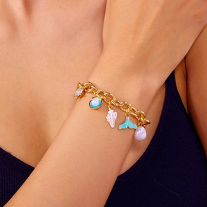 Detail of golden chain bracelet with sea shell, starfish, and blue fishtail charms