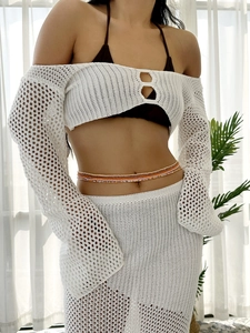 Detail of white crochet two-piece set with long sleeve crop top and hollow mesh long skirt