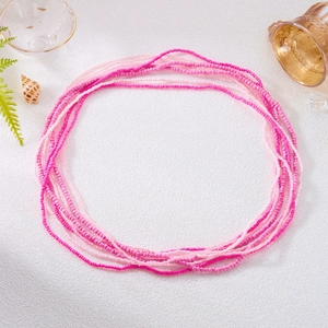 Top-down view of multilayered pink beaded waist chains with seashells and summer decor