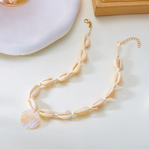 Dettaglio della collana bohémien di conchiglie con ciondolo perlato e chiusura dorata