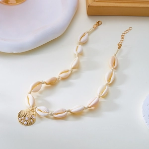 Dettaglio della collana con conchiglie intrecciate, ciondolo dorato e perle finte