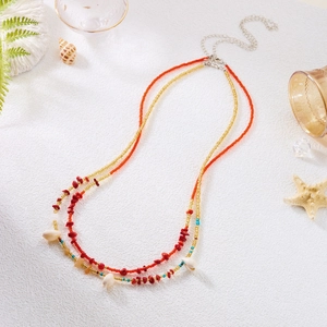 Close-up of bohemian beaded waist chain with red gravel stones and white sea shell charm
