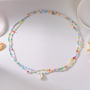 Detail of bohemian waist chain with colorful seed beads and a natural white shell charm