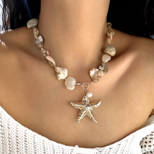 Close-up of bohemian necklace with golden starfish charm and iridescent shell fragments