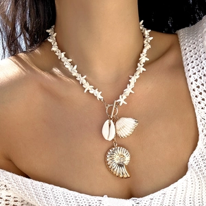 Detail of seashell and starfish necklace featuring golden nautilus pendant on a female model