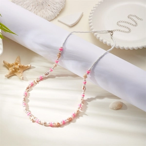 Detail of bohemian waist chain with shells, starfish, and pink beads on a beach decor