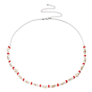Detail of bohemian waist chain with white beads, red spacers, and a seashell charm