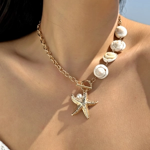 Detail of bohemian gold necklace with natural spiral shells and a starfish pendant