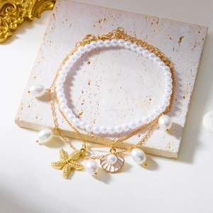 Detail view of double-layer anklet with gold starfish, shell charms and white pearls