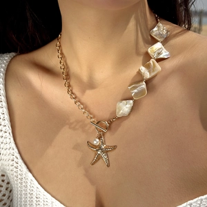Detail of bohemian starfish necklace with shell fragments and pearl on a female wearer