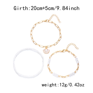 Close-up of three-piece set with shell and pearl charms on golden layered anklets