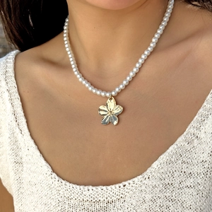 Vue détaillée d'un collier de perles blanches avec pendentif fleur dorée sur mannequin