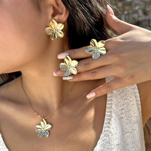 Gros plan d'un ensemble de bijoux fleurs dorées montrant les pétales texturés et l'éclat