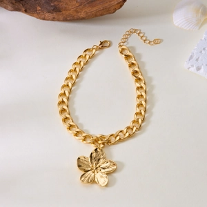 Détail macro du bracelet à maillons dorés avec pendentif fleur à cinq pétales texturés