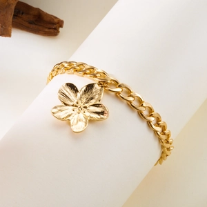 Détail macro du bracelet à breloque fleur dorée avec texture de chaîne élégante