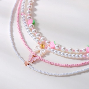 Detailaufnahme der Erdbeer-Halsketten mit rosa Schmetterlingen und Goldherzen