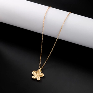Gros plan du pendentif fleur dorée avec texture de pétale sur socle blanc