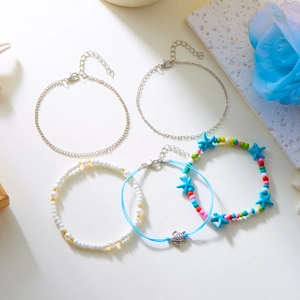 Close-up of layered beach anklets with starfish, turtle charms and colorful beads