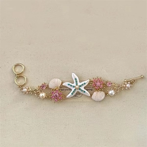 Hawaiian style gold necklace with colorful starfish, shells and pearls on beige texture
