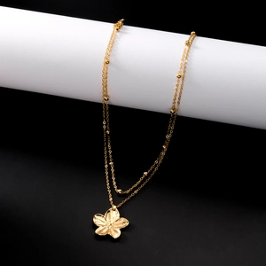 Gros plan du collier doré à deux rangs avec pendentif fleur et petites billes