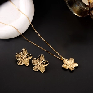 Détail macro du parure bijoux fleur dorée avec texture en métal brossé sur fond sombre