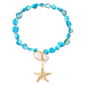 Detailed shot of starfish, seashell, and pearl charms on turquoise bead layered necklace
