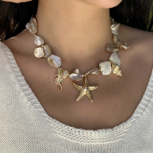 Detailed close-up of baroque pearl necklace with golden starfish and seashell pendants
