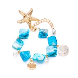 Macro shot of gold starfish and seashell charms on a layered faux pearl and blue bead chain