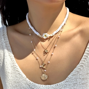Detail of four-layer bohemian necklace with plumeria, palm tree, and seashell pendants