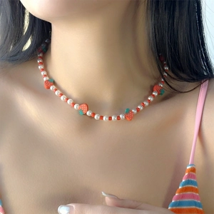 Dettaglio della collana di fragole con perle e ciondoli colorati su una modella