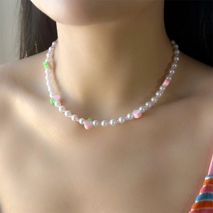 Dettaglio di una collana di perle con ciondoli a fragola sul collo di una modella
