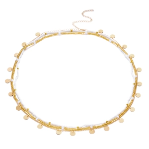 Close-up of bohemian multilayer gold chain with white beads and metallic disc pendants