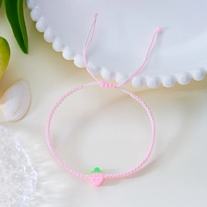 Detail eines handgewebten Armbands mit Erdbeer-Anhänger und verstellbarer Kordel