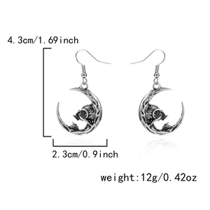Detail view of silver gothic moon and skull earrings with specific size and weight data