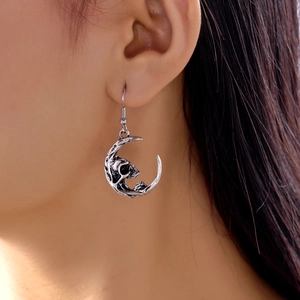 Close-up of gothic silver crescent moon earrings with realistic skull detail for women
