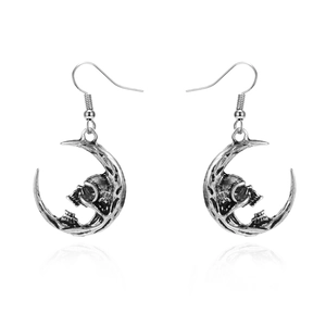 Close-up of vintage silver skull and moon drop earrings with gothic punk oxidized details