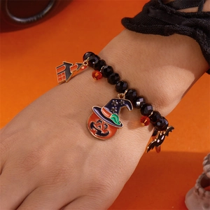 Pulsera de cuentas de Halloween con dijes de calabaza y murciélago sobre fondo naranja
