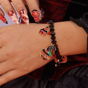Detalle de pulsera de Halloween con dijes de calabaza y sombrero de bruja en la muñeca