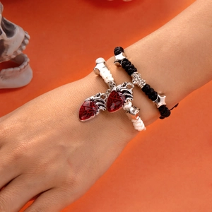 Detail von geflochtenen Armbändern mit roten Herzanhängern und silbernen Sternen