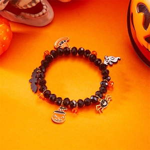 Detalle de pulsera de Halloween con cuentas y colgantes de calabaza y araña sobre fondo naranja