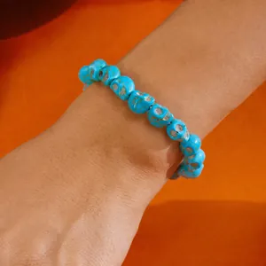 Primer plano detallado de una pulsera de cuentas de calavera azul sobre fondo naranja intenso