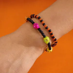Detalle de pulseras de cuentas de Halloween con calaveras de colores en la muñeca