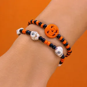 Detalle del juego de pulseras de Halloween con dije de calabaza y colgantes de calavera