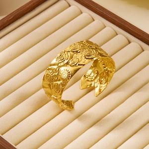 Close-up of gold open cuff bracelet with embossed sun face design on jewelry box