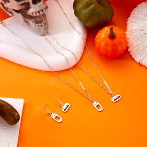 Details von silbernen Geisteranhängern für Halloween-Schmucksets vor orangefarbenem Hintergrund