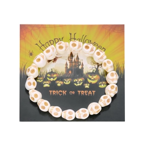 Detalle de pulsera de calaveras para Halloween sobre tarjeta festiva con motivos de calabaza