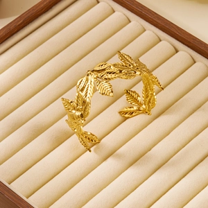 Detail of golden laurel leaf texture open cuff bracelet in a beige velvet jewelry box
