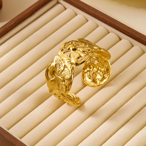 Detailed view of a gold-plated open cuff bracelet featuring intricate bee carvings